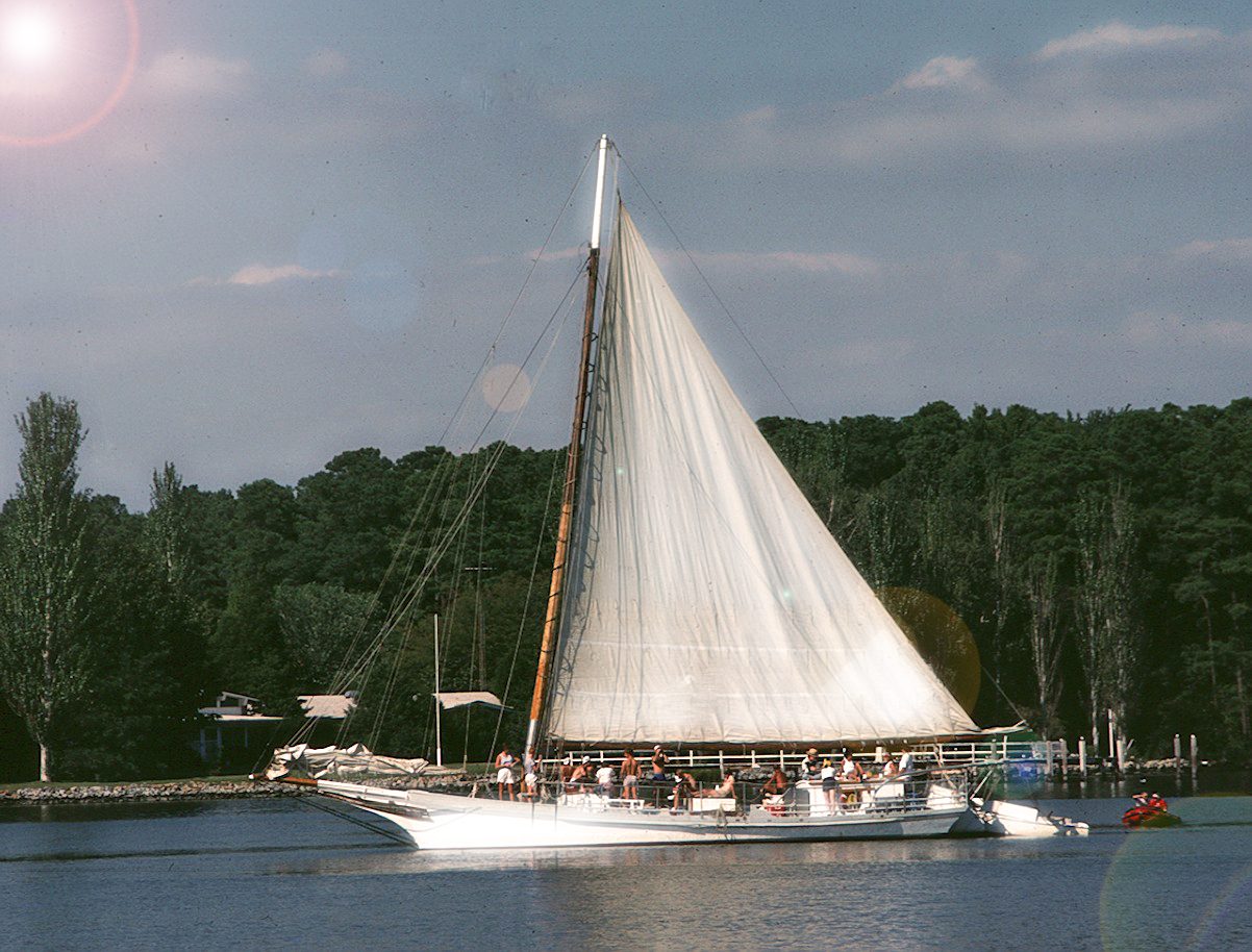 A sail boat with people on it in the water.