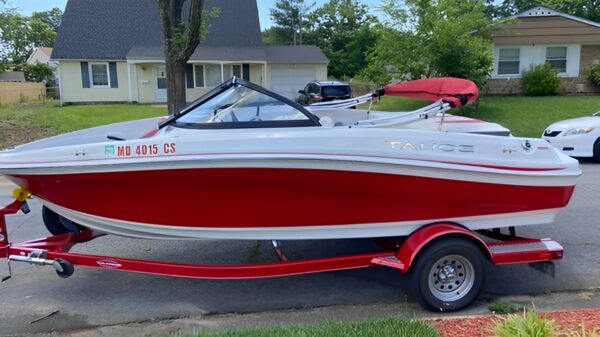 A red and white boat is parked on the street.