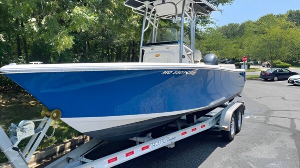 A boat is parked on the street with its trailer.