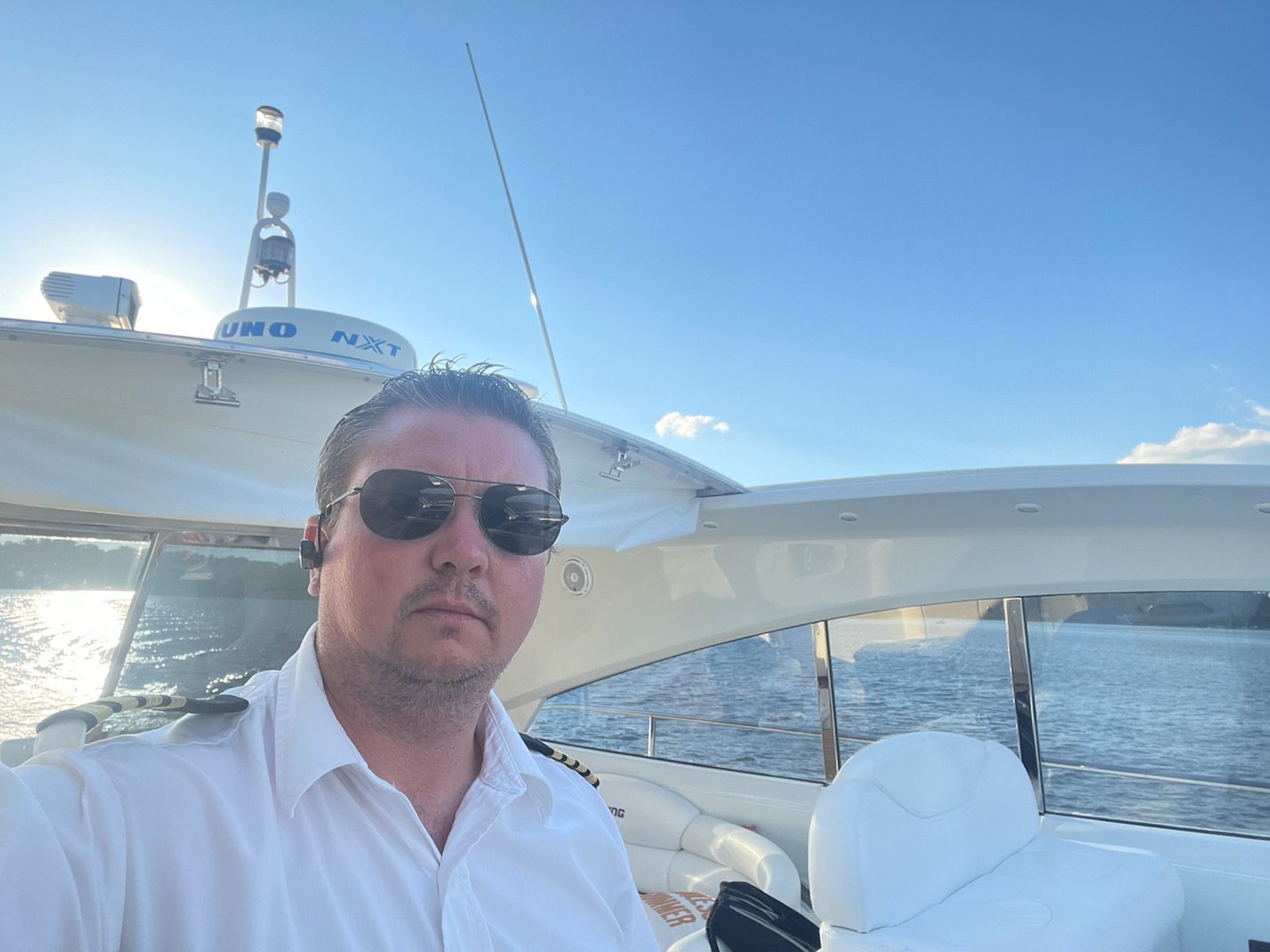 A man in sunglasses and white shirt on boat.