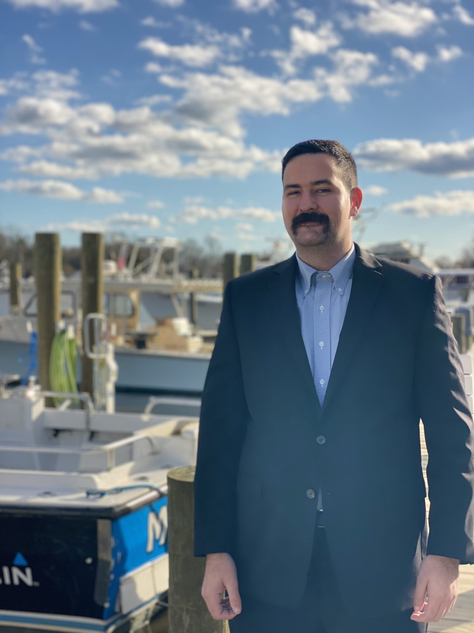 IMG_9234 A man in a suit standing next to boats.