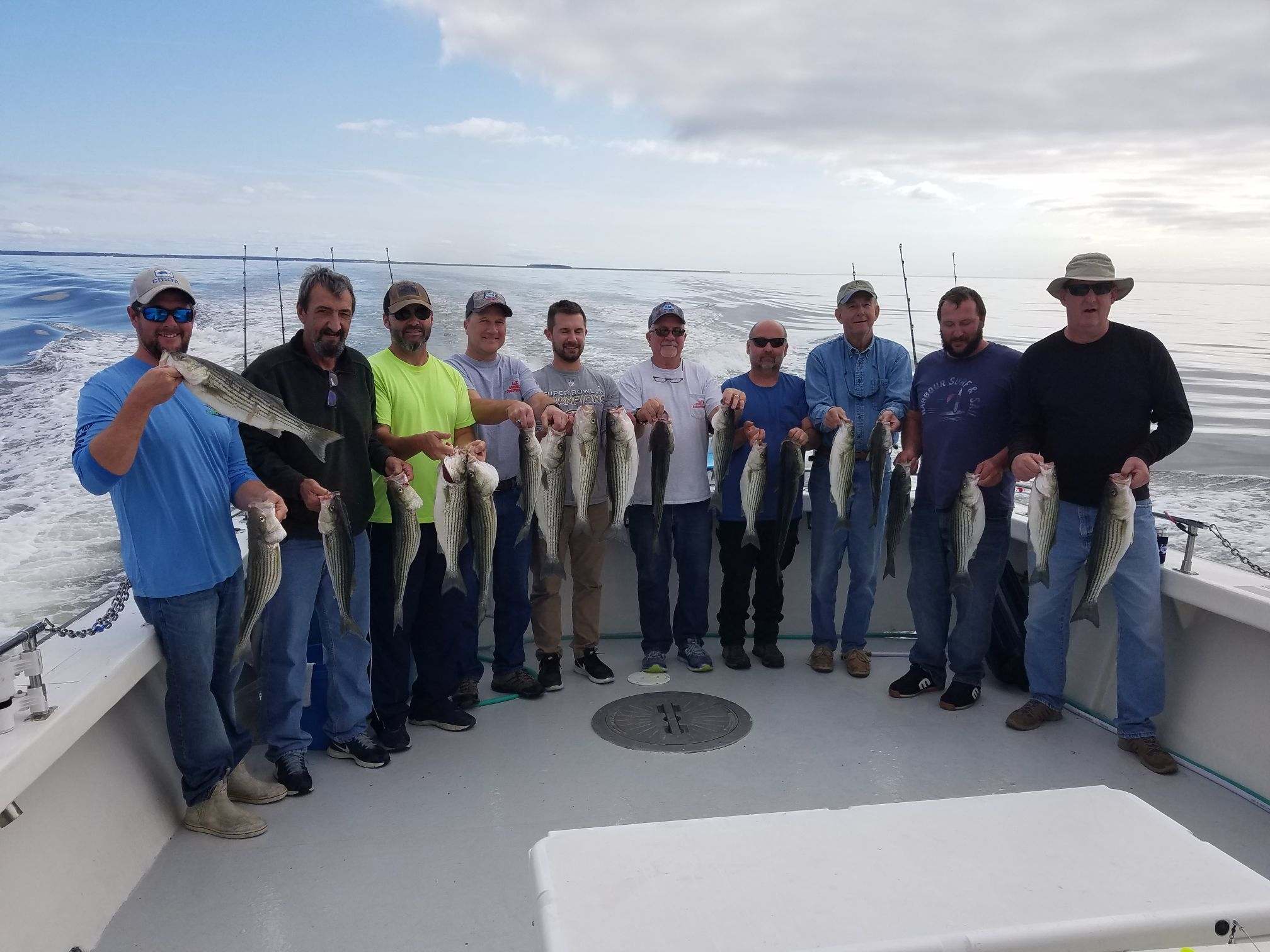 A group of men holding fish on top of a boat.