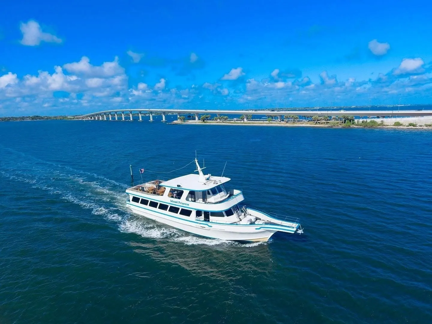 White yacht cruising near coastal bridge