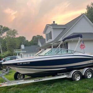 A boat is parked on the trailer in front of a house.