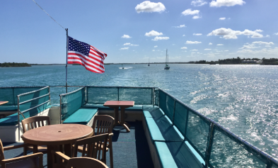 Sunlit boat deck, American flag, distant sailboats