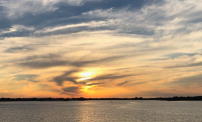 Sunset over tranquil lake with wispy clouds